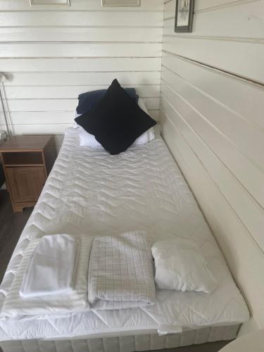 a white bed with a black pillow and pillows on it at Hulduhólar Cabin - The Elf Hills. in Selfoss
