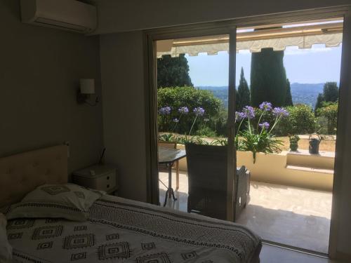 Clim Jardin et parking privé -piscine tennis et Park Vue mer في جراس: غرفة نوم بها سرير ونافذة ذات إطلالة