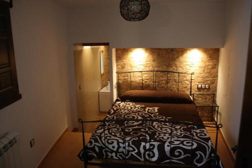 a bed in a bedroom with a stone wall at Casa Rural el Argen in Segorbe