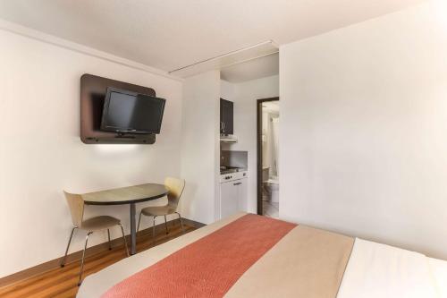 a bedroom with a bed and a table with a tv on the wall at Motel 6-Lethbridge, AB in Lethbridge