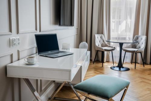 a white desk with a laptop on it and chairs at H Aparthotel in Ełk