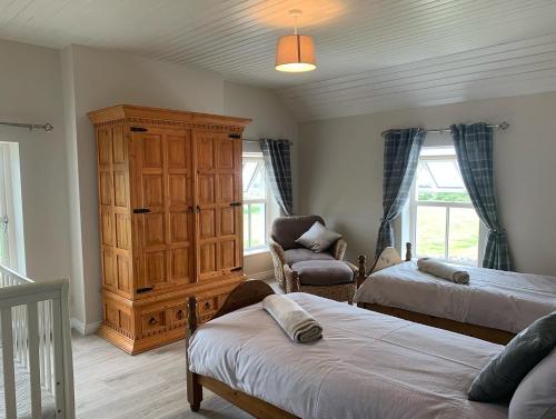 a bedroom with two beds and a cabinet and a chair at Sage Gables Mourne Mountains in Annalong