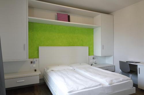 a bedroom with a white bed and a green wall at Eco Hotel Benacus in Malcesine