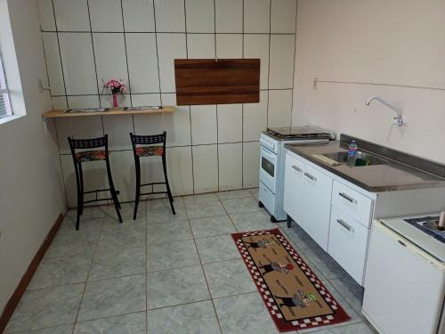 a kitchen with a stove and a sink and two chairs at Apartamento com churrasqueira, ótima localização. in Cachoeira do Sul
