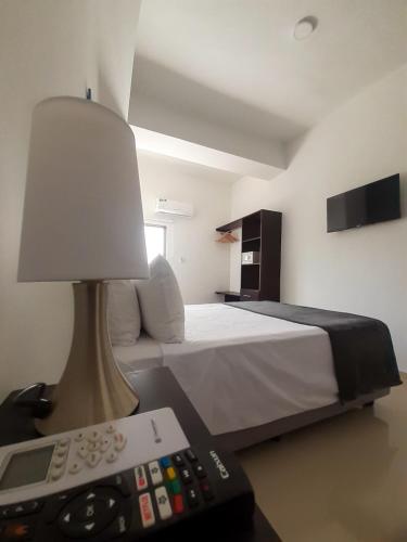 a bedroom with a bed with a lamp and a remote control at Hotel El Marqués De Manga in Cartagena de Indias