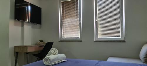 a bedroom with a bed and a desk and two windows at G&G Suites in Ohrid