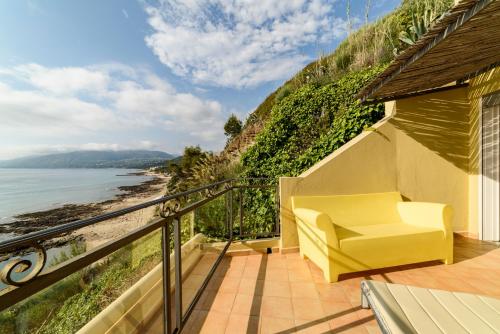 a yellow chair sitting on a balcony overlooking the ocean at Grand Hotel San Pietro in Palinuro