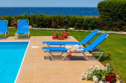 een groep blauwe ligstoelen naast een zwembad bij Diana Seaside Villas in Pomos