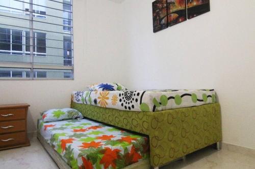 un sofá verde sentado en una habitación con cama en Relájate o teletrabaja en lindo apto, 3 hab y WiFi, en Villavicencio