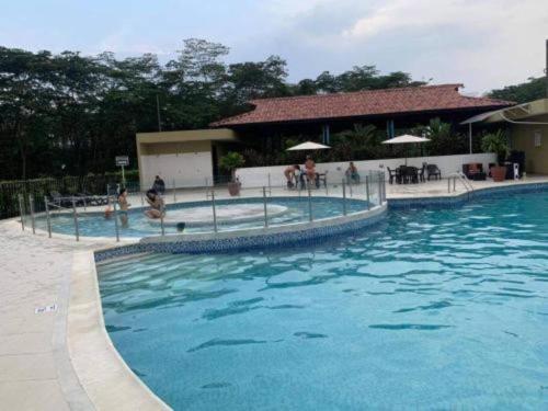 a large blue swimming pool with people sitting around it at Relájate o teletrabaja en lindo apto, 3 hab y WiFi in Villavicencio