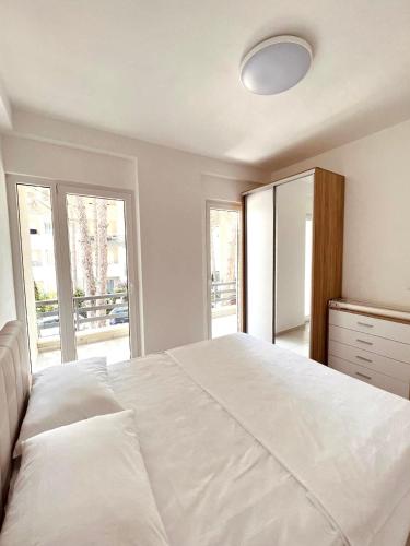 a bedroom with a large white bed and a mirror at Pine Breeze Apartment Gjiri i Lalezit in Draç