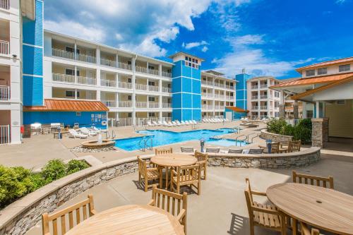 an outdoor patio with tables and chairs and a pool at The Sanctuary - Summer Breeze A114 in Virginia Beach