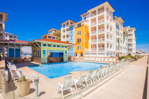 a swimming pool with chairs in front of some apartment buildings at The Sanctuary - Summer Breeze A114 in Virginia Beach