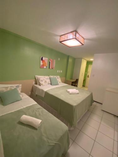 two beds in a room with green walls at Barreirinhas Flat Gran Solare 210 in Barreirinhas