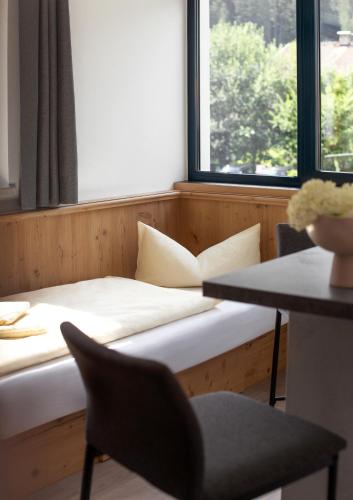 a room with a bed and a desk and a window at Hotel & Suites Glück Auf in Mayrhofen