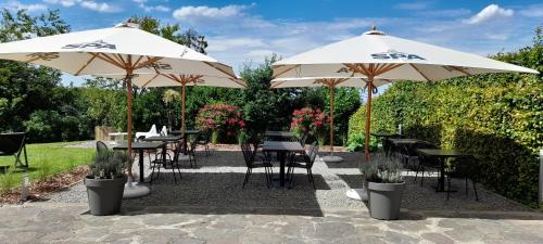 two tables and chairs under umbrellas in a garden at La Ferme du Soyeuru in Spa