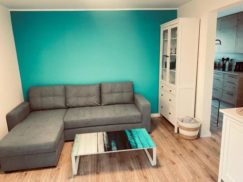 a living room with a couch and a blue wall at Apartament Turkusowy in Puck