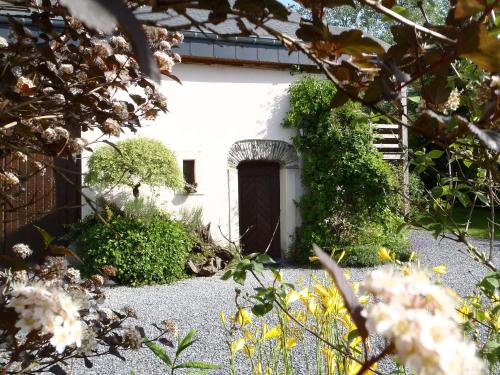 a white house with a door in a garden at Gites-Clairiere-Ardenne in Louftémont