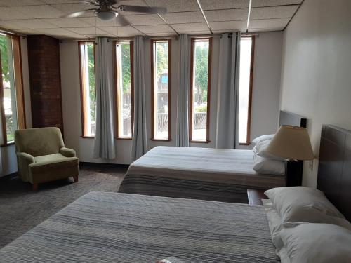 a bedroom with two beds and a chair and windows at Mountain View Lodge in Clifford