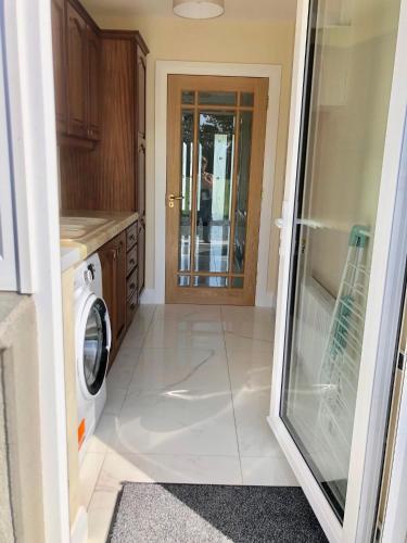 a laundry room with a washer and a glass door at Loughgunnen Grove Lodge in Wexford