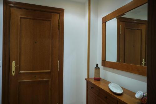 uma casa de banho com uma porta de madeira, um lavatório e um espelho. em Apartamento Cabanilles em Villaviciosa