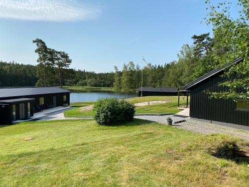 a black building with a lake in the background at Gråbogården event and conference center in Gråbo