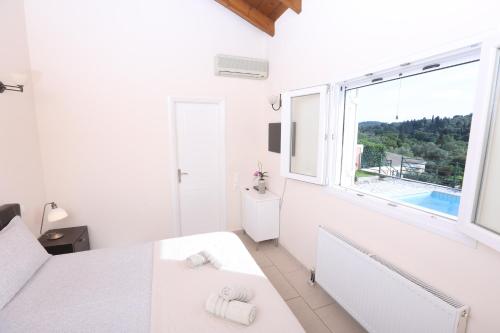 Villa Sophia في مدينة كورفو: غرفة بيضاء مع سرير وحوض استحمام ونافذة