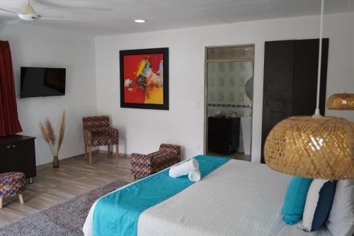 a bedroom with a bed and a tv and chairs at Villeta Boutique Hotel Spa in Villeta