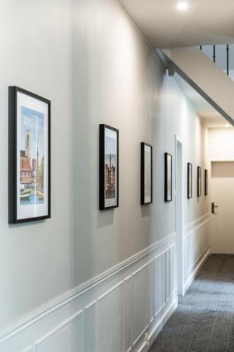 a hallway with framed art on the walls at La Castagnère de Bergory in Wervicq-Sud