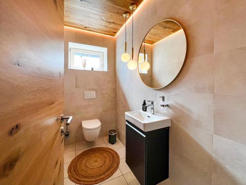La salle de bains est pourvue d'un lavabo, d'un miroir et de toilettes. dans l'établissement Mid Mountain Apartment Tirol, à Wiesing