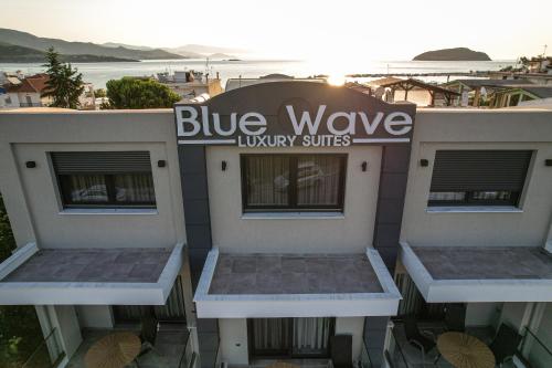 luksusowe apartamenty typu suite z niebieską falą podpisane na boku budynku w obiekcie Blue Wave Luxury Suites w mieście Iraklitsa