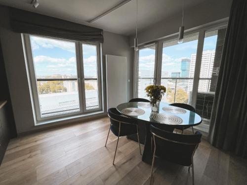 a dining room with a table and chairs and large windows at Apartament in Katowice