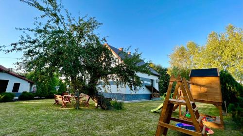 un patio con un árbol y un parque infantil en Aparthotel w Dolinie Stawów Zator by Housine, en Las