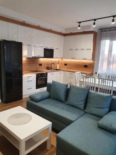 a living room with a blue couch and a kitchen at Apartament na Letniej z garażem "Domowe Zacisze" in Kłodzko