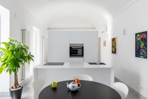 a white kitchen with a black table and chairs at Suite Bellini 5 Apartment in Palermo