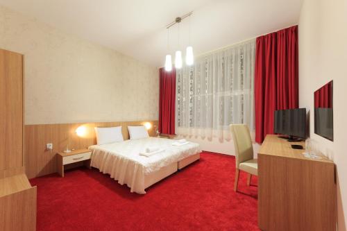 a hotel room with a bed and a desk and a television at Sky Hotel in Veliko Tŭrnovo