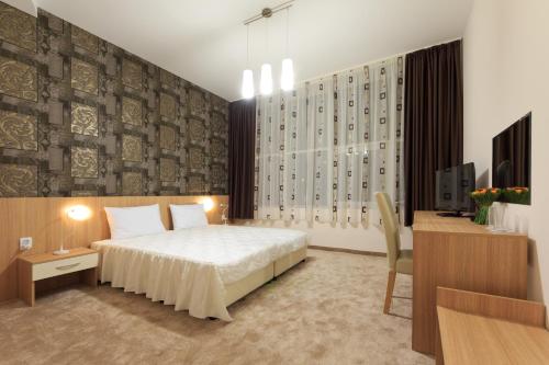 a bedroom with a bed and a tv and a desk at Sky Hotel in Veliko Tŭrnovo
