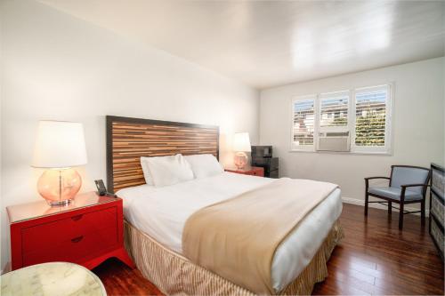 a bedroom with a large white bed and a chair at Hollywood Downtowner Inn in Los Angeles