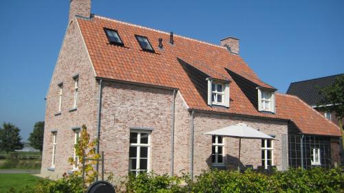 a brick house with an orange roof and an umbrella at B&B Het Postenhofje in Puiflijk