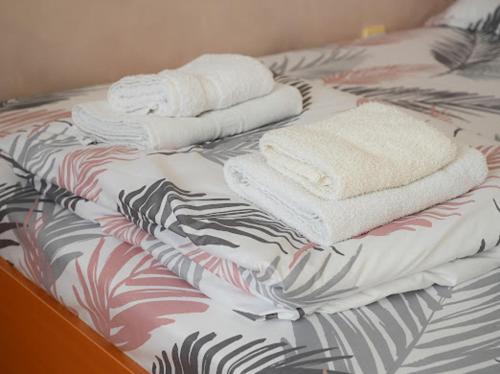 a bed with three towels on top of it at MB Apartments in Jagodina