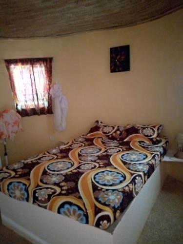 a bedroom with a bed with a colorful blanket at Campement Baobab chambres d'hotes 15mn de l'aeroport in Poponguine