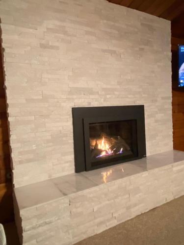 a brick fireplace with a fire in it at April Point Harbour House in Quathiaski Cove