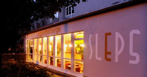 a lit up building with lights in the windows at Hostel SLEPS in Augsburg