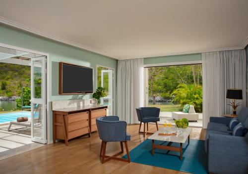 a living room with a tv and a blue couch at St Martin Beach Resort & Spa in Anse Marcel 