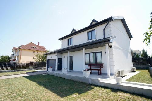 a white house with a bench in a yard at Casa Canadiana in Baile Felix
