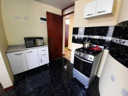 a black and white kitchen with a stove and a microwave at Departamento amoblado en Arequipa, Yanahuara in Yanahuara