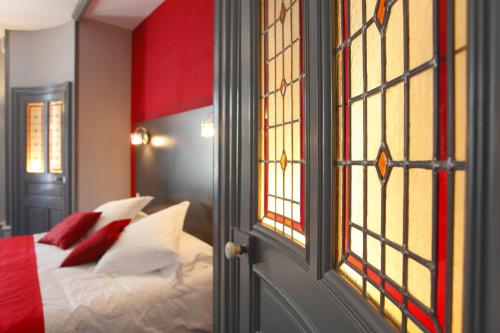 a bedroom with a bed with red and white pillows at Hotel Château de la Barbinière in Saint-Laurent-sur-Sèvre