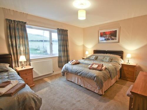 a bedroom with two beds and a large window at Cob Cottage in Tregaron