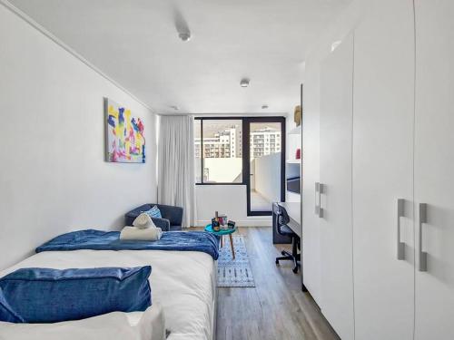 a white bedroom with a bed and a desk in it at Cozy, Work Station, Wi-Fi, Patio in Cape Town
