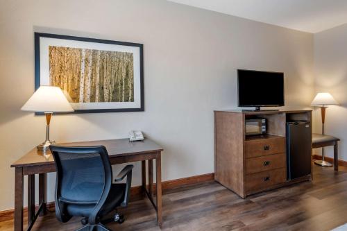 a room with a desk and a tv and a desk and chair at Best Western Desert Inn in West Yellowstone